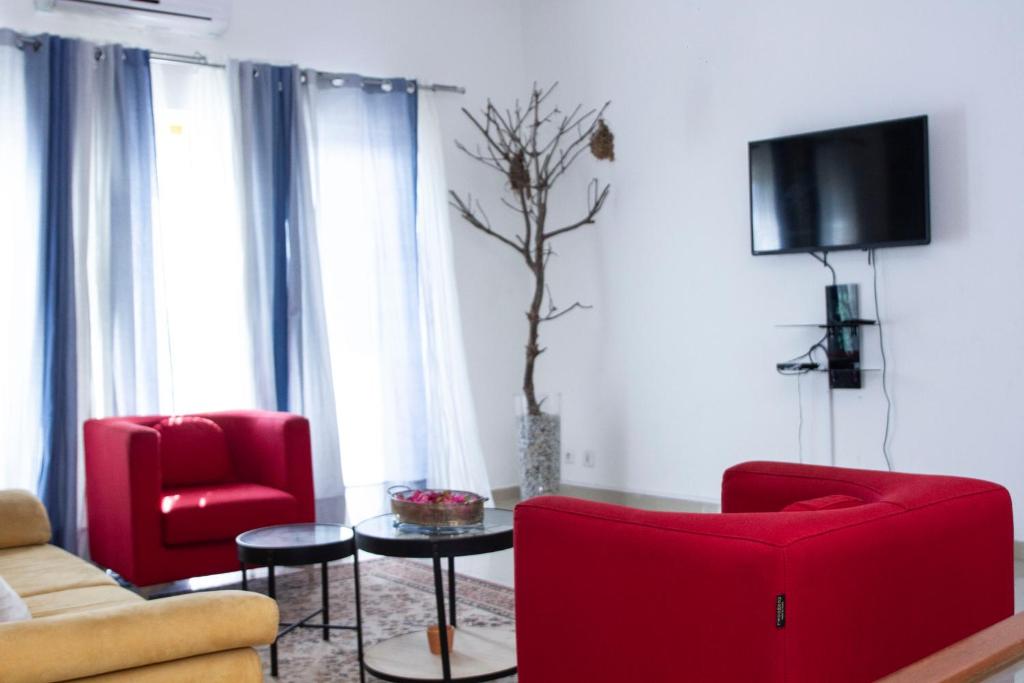 ein Wohnzimmer mit 2 roten Stühlen und einem TV in der Unterkunft RESIDENCE rubis in Cotonou