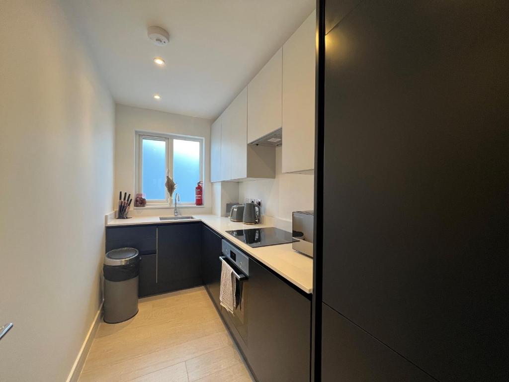 a kitchen with white cabinets and a sink and a window at Star London Station Road 3-Bed Haven in London