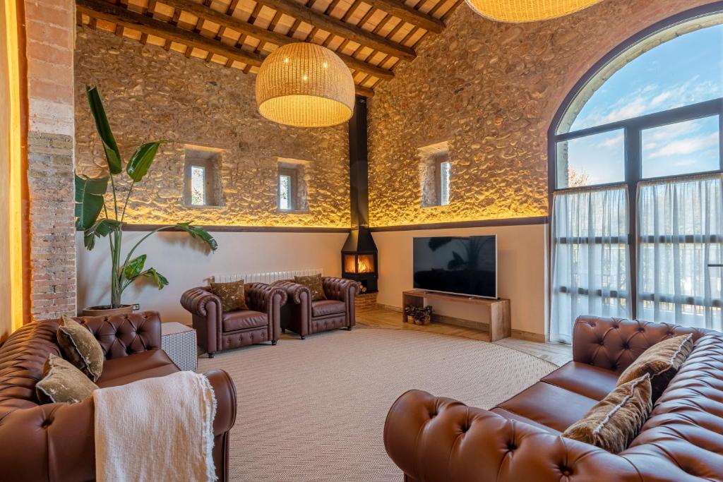 sala de estar con sofás de cuero y TV de pantalla plana en Masos Can Sot, en Pont de Molins