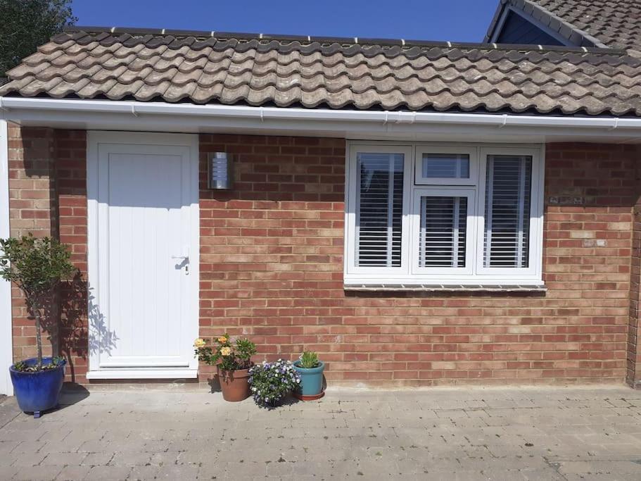 a brick house with a white door and potted plants at The Studio in Felpham