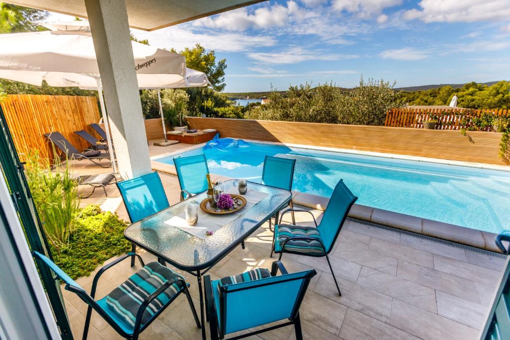 a patio with a table and chairs next to a swimming pool at Villa NONO Jure - Private Pool & Jacuzzi, Milna Brač in Milna