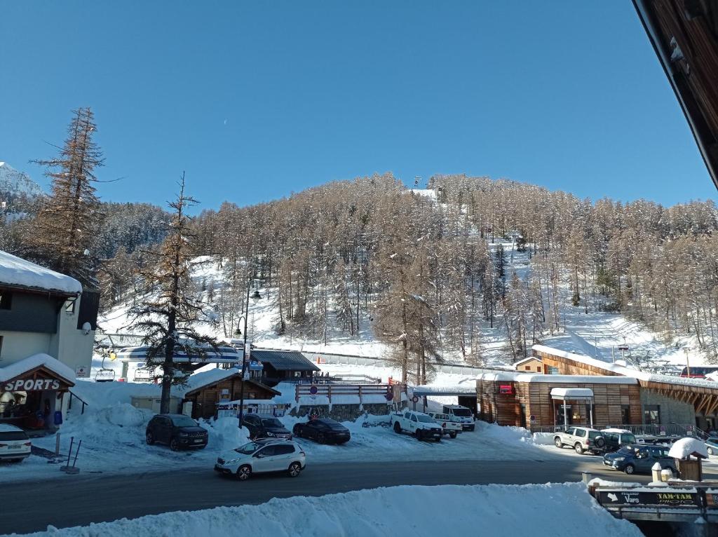 een parkeerplaats met een met sneeuw bedekte berg op de achtergrond bij Résidence le Schuss Studio Montagne en bas des pistes in Vars