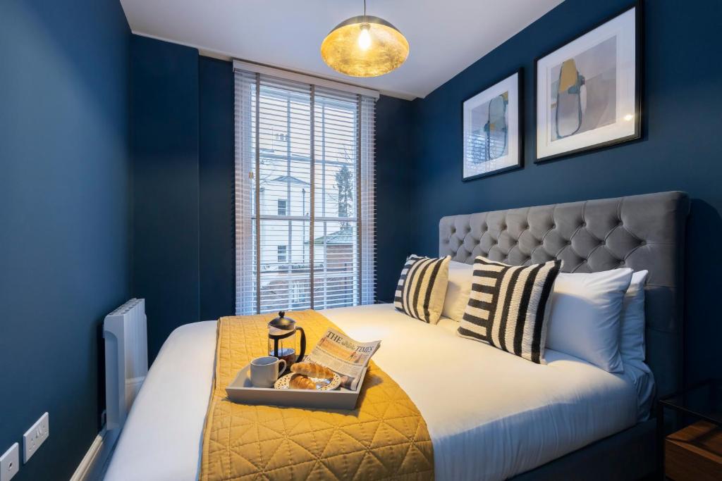 a blue bedroom with a bed with a tray of food on it at Elliot Oliver - Luxury 2 Bedroom Regency Apartment With Parking & EV Charger in Cheltenham
