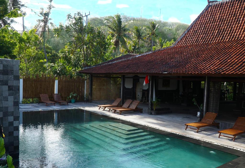 a swimming pool with chairs and a house at Lost Paradise Gili in Gili Trawangan