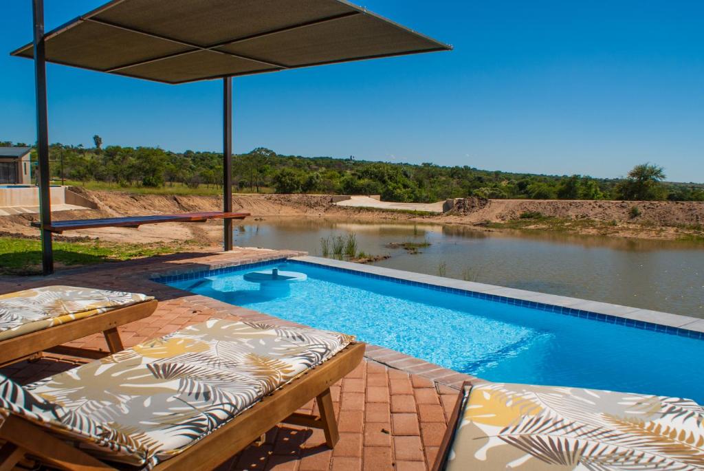 a swimming pool with two lounge chairs and an umbrella at Casa de la Presa 4 in Polokwane