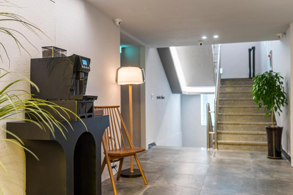 a hallway with stairs and a chair and a lamp at Jawoori Hotel Incheon Songdo in Incheon