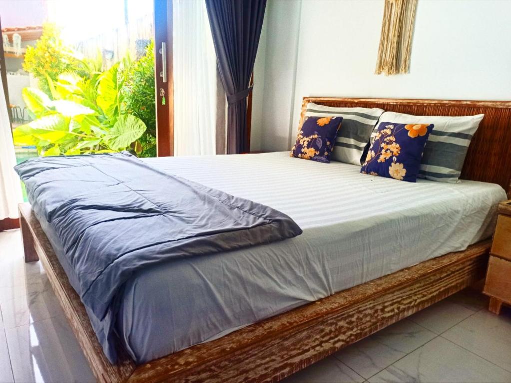 a wooden bed with blue pillows in a bedroom at Loka Anyar Guest House in Kerobokan