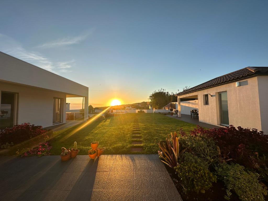 a house with the sun setting in the yard at Serenity Azores - Casa da Aldeia in Nordestinho