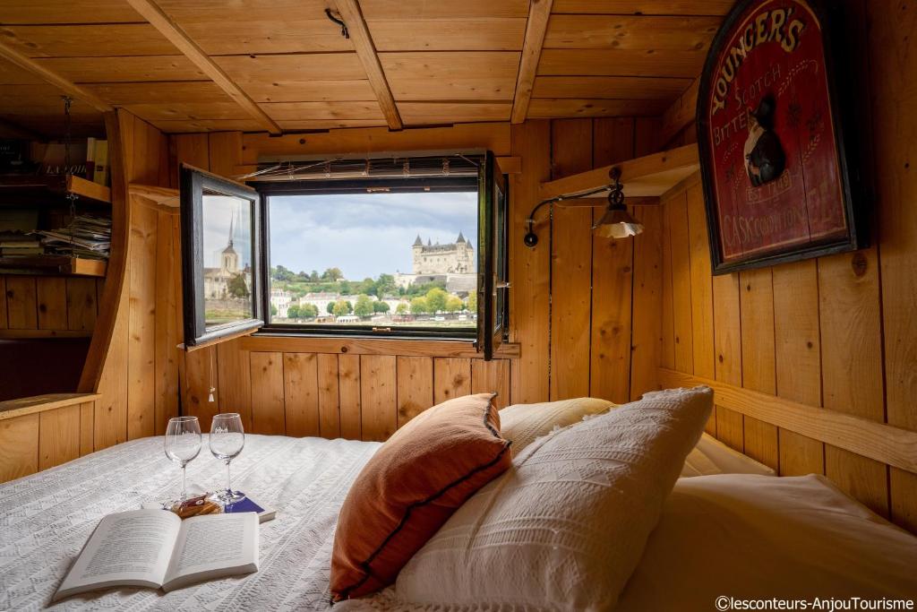 a bedroom with a bed with a window and two wine glasses at BATEAU LE VENT DE TRAVERS in Saumur