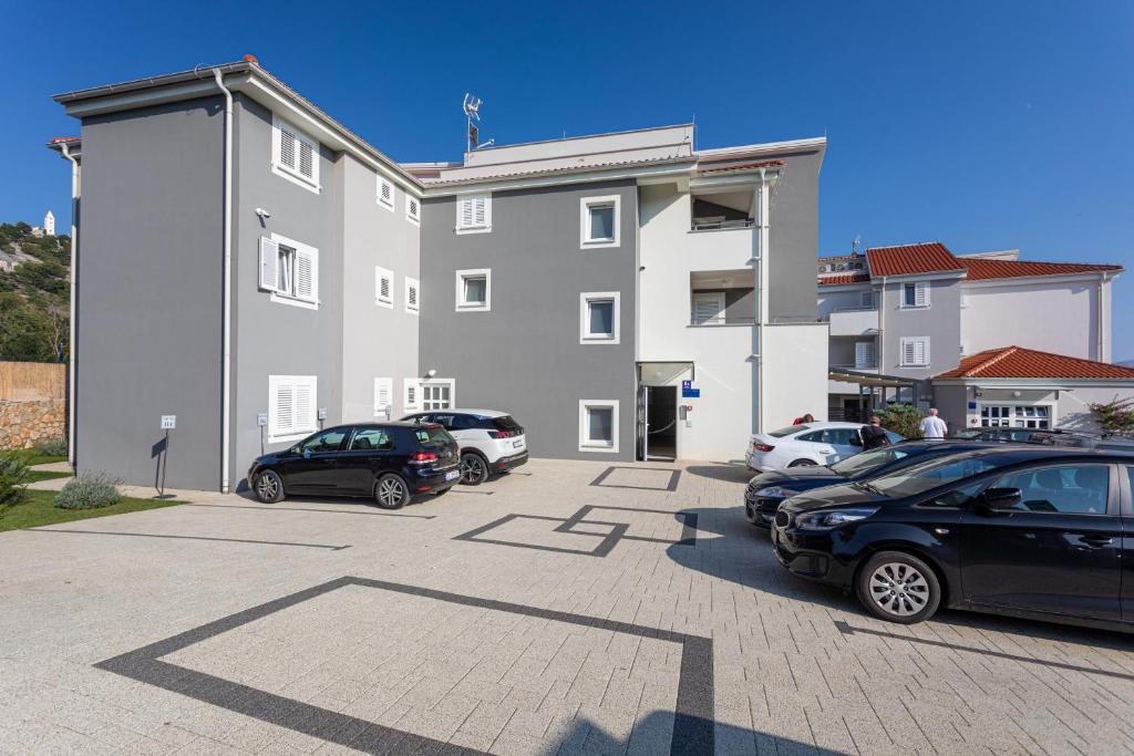 a parking lot with cars parked in front of a building at Apartments Crnekovic Tomislava 8A in Baška