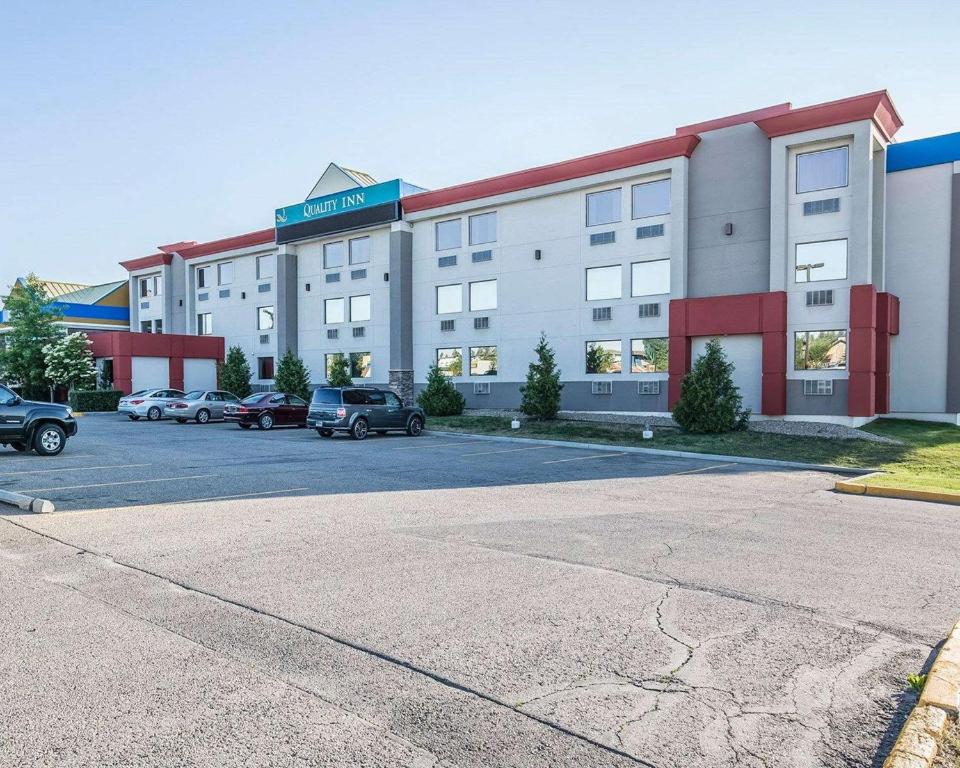ein großes Gebäude mit auf einem Parkplatz abgestellten Autos in der Unterkunft Quality Inn & Conference Centre in Red Deer