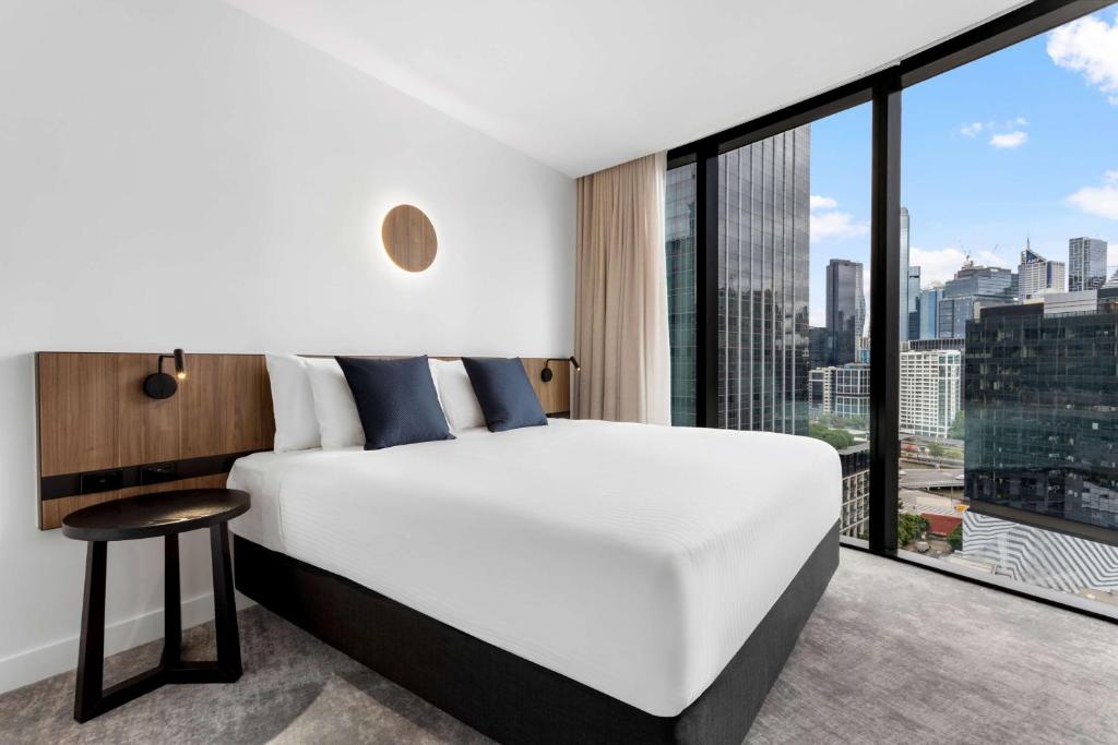 a bedroom with a white bed and a large window at Adina Apartment Hotel Melbourne Southbank in Melbourne