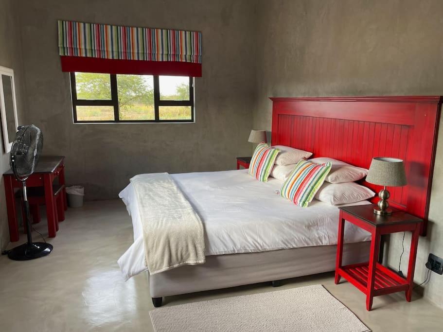 a bedroom with a large bed with a red headboard at The Barnhouse in Hammanskraal