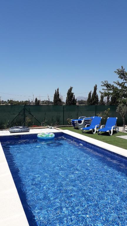 a swimming pool with two blue chairs next to it at Eco Resort Costa Blanca in Dolores