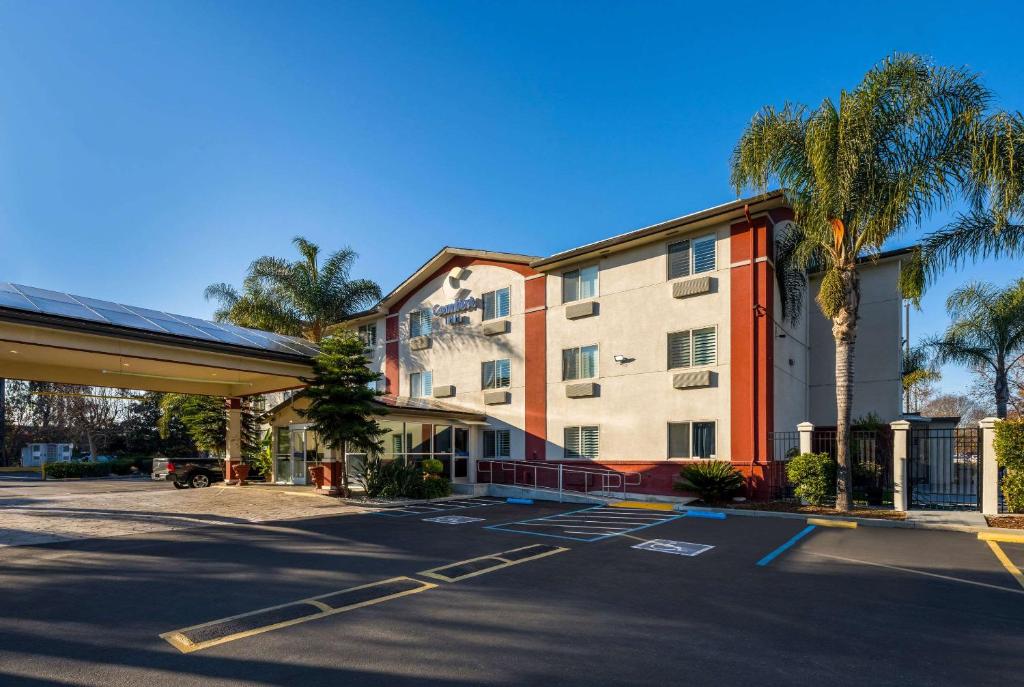 a building with palm trees in a parking lot at Comfort Inn Gilroy in Gilroy