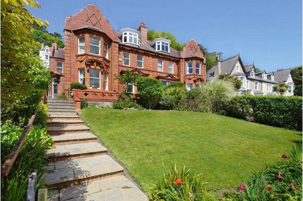 ein großes Backsteinhaus mit Rasen davor in der Unterkunft St Katherines in Llandudno