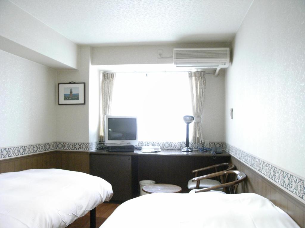 Habitación con 2 camas, TV y ventana. en Sunplaza Rinkai, en Osaka