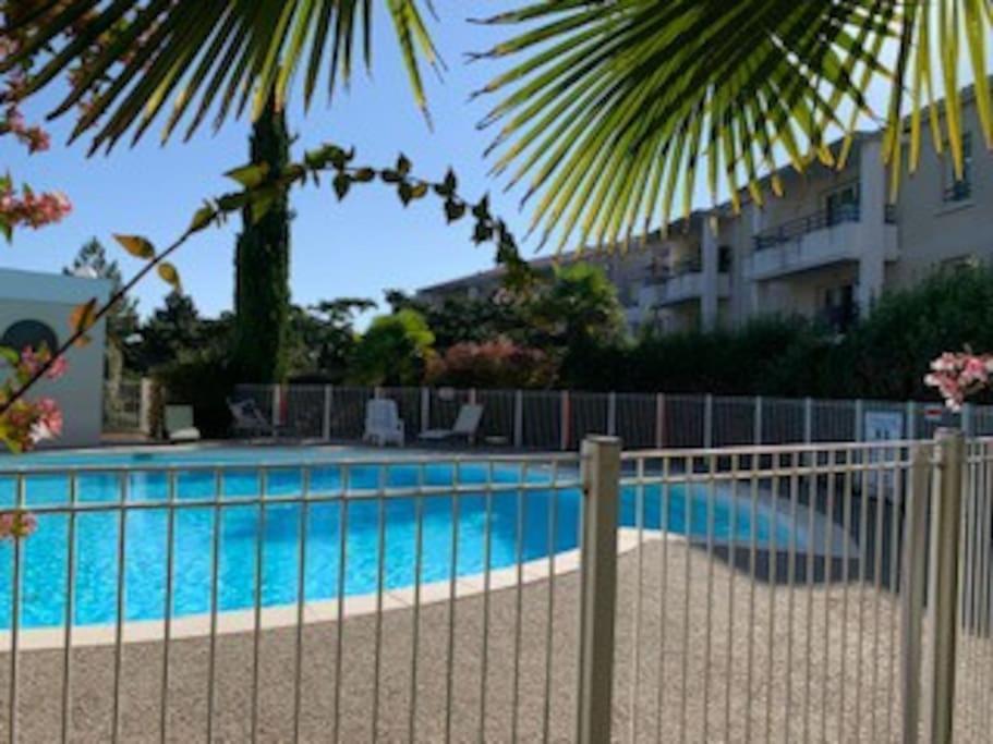 een zwembad met een hek naast een gebouw bij Appartement à Royan avec accès piscine in Royan