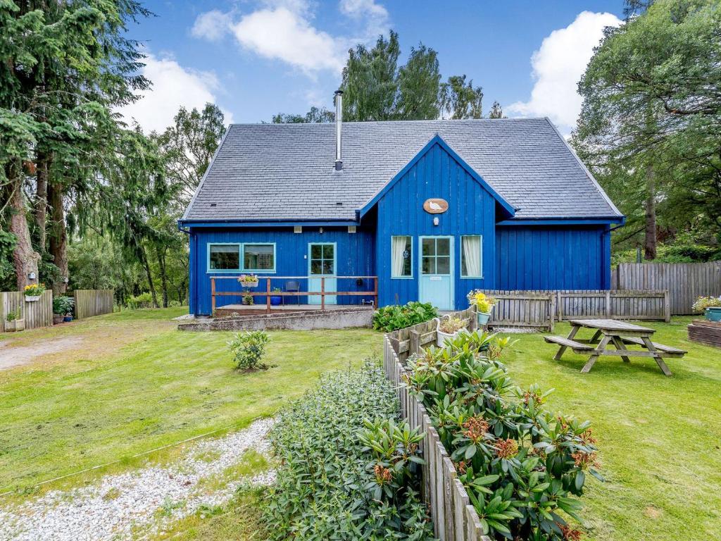una casa blu con un tavolo da picnic nel cortile di Ptarmigan Cottage-ukc5518 a Boat of Garten