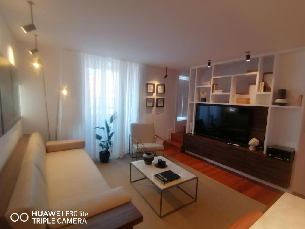 ein Wohnzimmer mit einem Sofa und einem TV in der Unterkunft Timeless - Energy - Belém in Lissabon