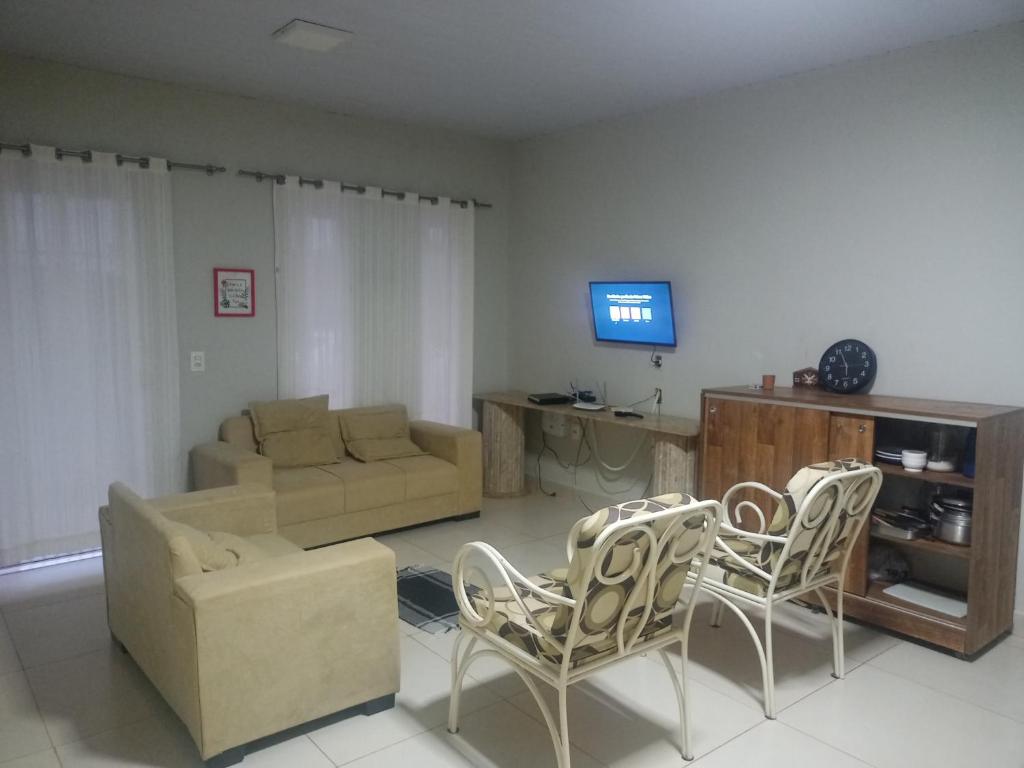 sala de estar con sofá, sillas y TV en Casa com 03 quartos tendo 02 com ar condicionado no asfalto a 1,5 km do centro, en Chapada dos Guimarães