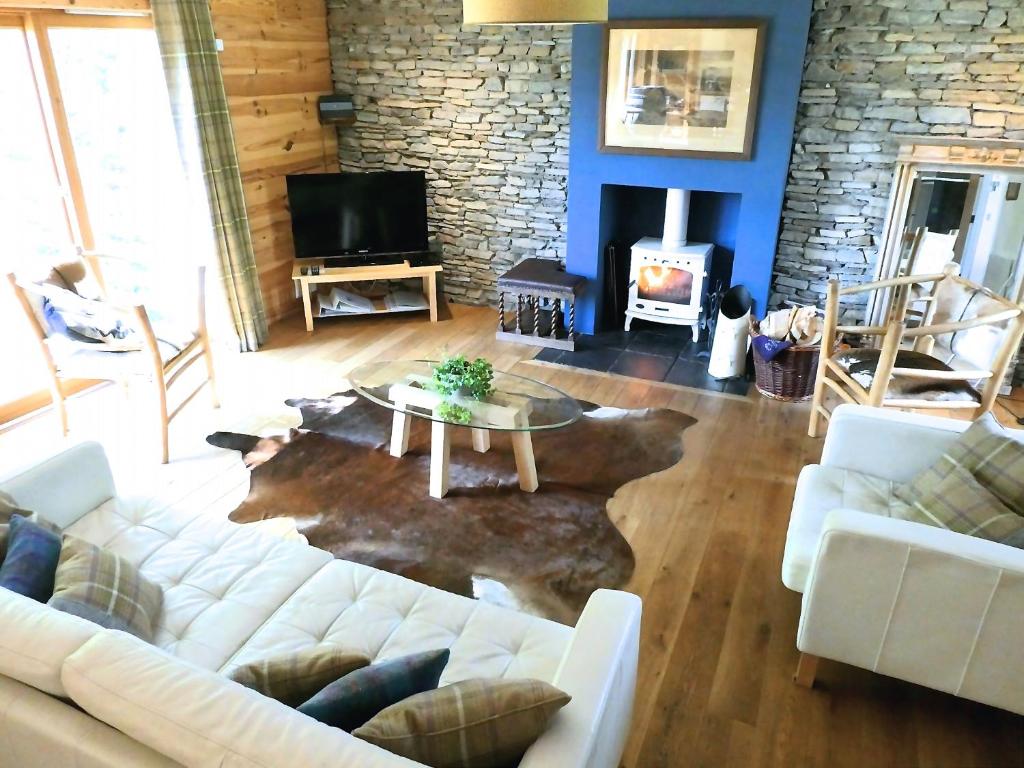 a living room with a couch and a table and a fireplace at The Byre - by Where Stags Roar in Newtonmore