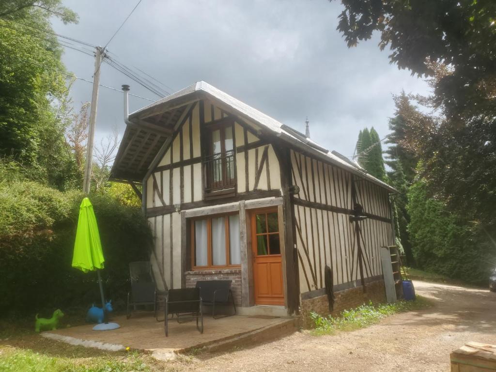 een klein huis met een oranje deur en een patio bij HAMPTON COTTAGE in Aubry-le-Panthou