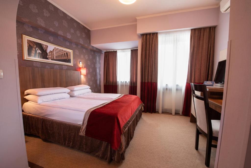 a hotel room with a bed and a desk at Hotel Ambasador in Bucharest