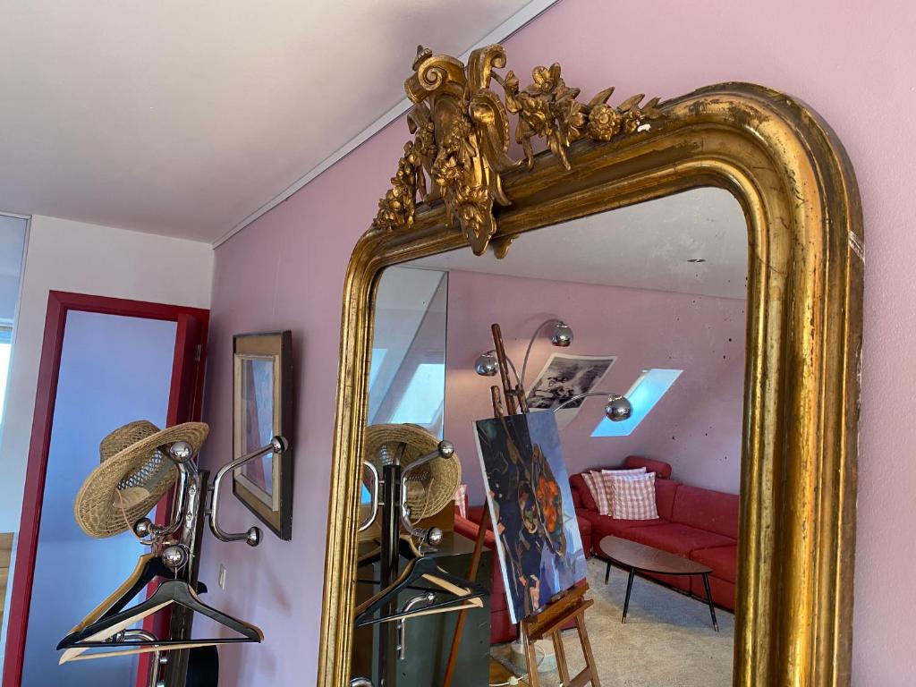 a gold mirror in a room with a red couch at Artist's Loft & Garden in Ghent