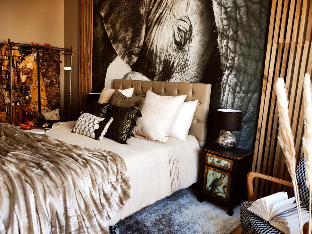 1 dormitorio con 1 cama con una pintura de elefante en la pared en Appartements design - Uniques - Centre, en Bagnères-de-Bigorre