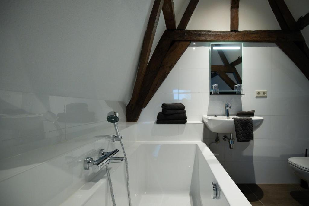Baño blanco con bañera y lavamanos en Logement de Spaerpot en Middelburg