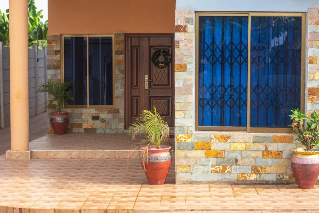 Afranasa Inn في تيما: منزل به نباتات الفخار أمام الباب