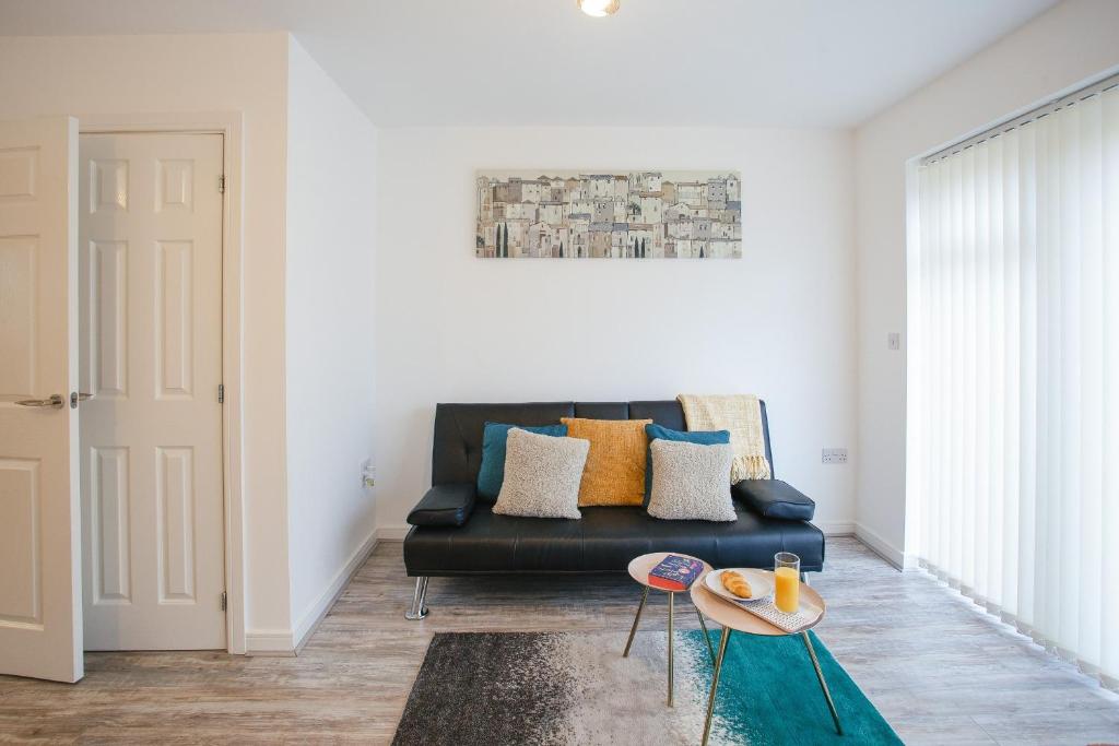 a living room with a black couch and a table at Cosy 2-bed home - For Company contractor and Leisure stays - NEC, Airport, HS2, Contractors, Resort World in Marston Green
