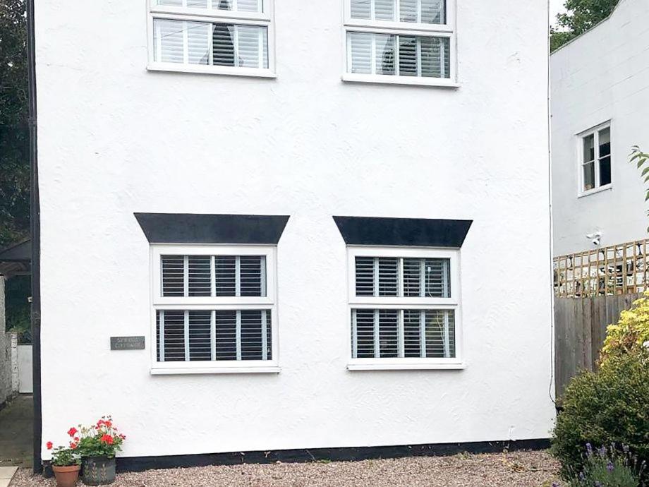 ein weißes Haus mit drei Fenstern und einem Zaun in der Unterkunft Spring Cottage in Parkgate