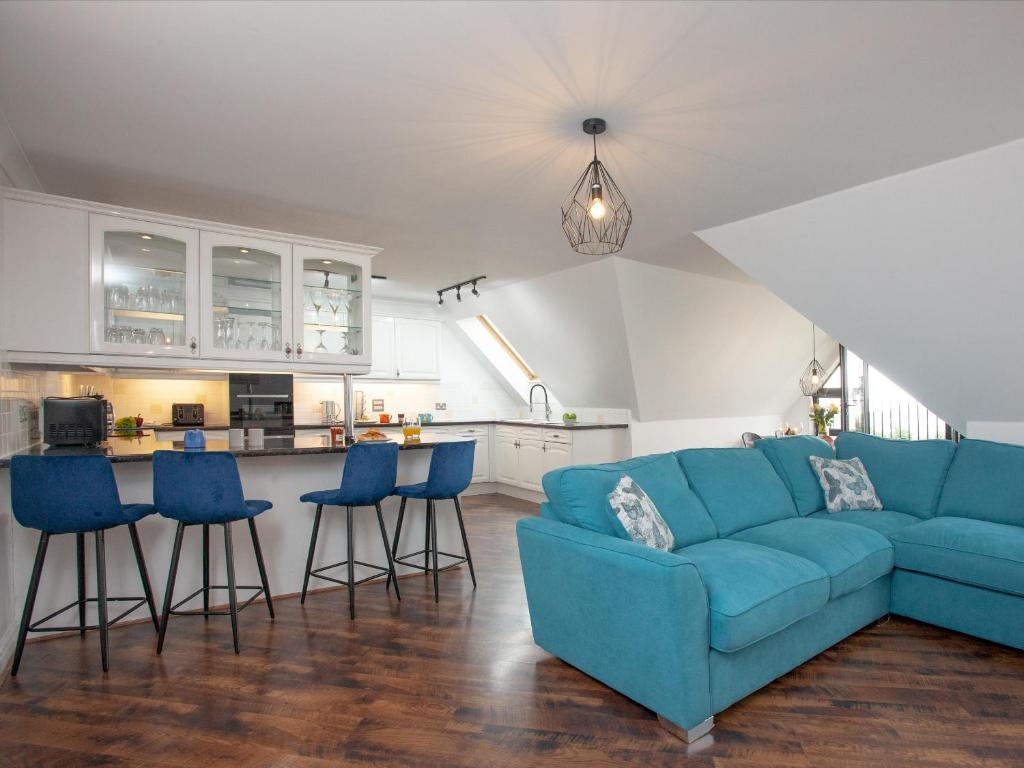 sala de estar con sofá azul y cocina en Pochin House Apartment 16 en St Austell