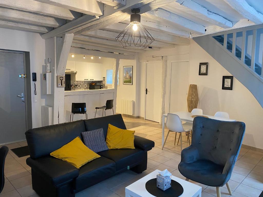 a living room with a black couch and a table at Le Marais Vous - Duplex en centre-ville. in Provins