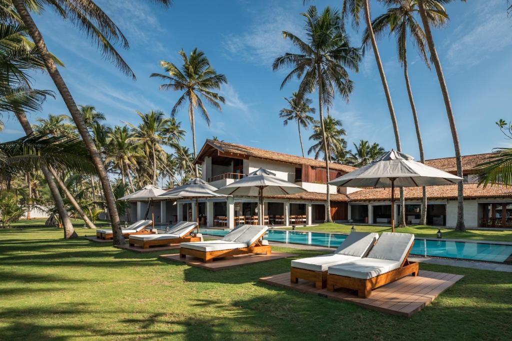 um resort com uma fila de espreguiçadeiras e uma piscina em Villa Thamburu, Bentota em Bentota