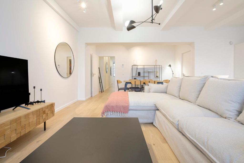 uma sala de estar com um sofá branco e uma televisão em Appartement design 3 chambres proximité Grand-Place Bruxelles em Bruxelas