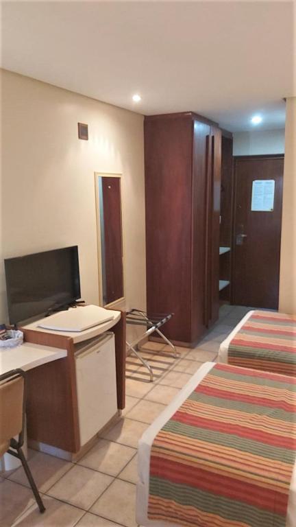 a hotel room with two beds and a desk and a mirror at Pousada dos Girassóis in Palmas