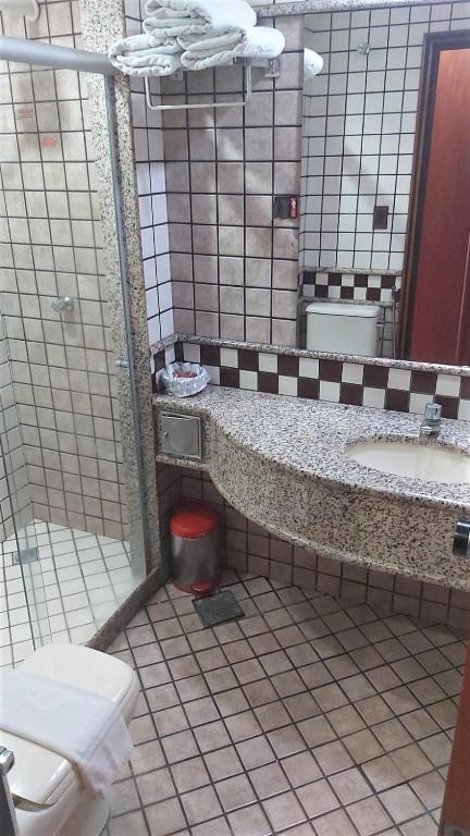 a bathroom with a toilet and a sink and a mirror at Pousada dos Girassóis in Palmas
