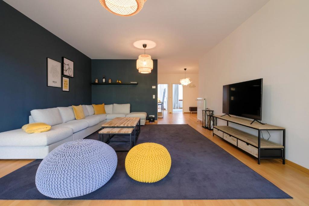 sala de estar con sofá blanco y TV en Chaleureux appartement 1 chambre proche Ecole Européenne, en Bruselas