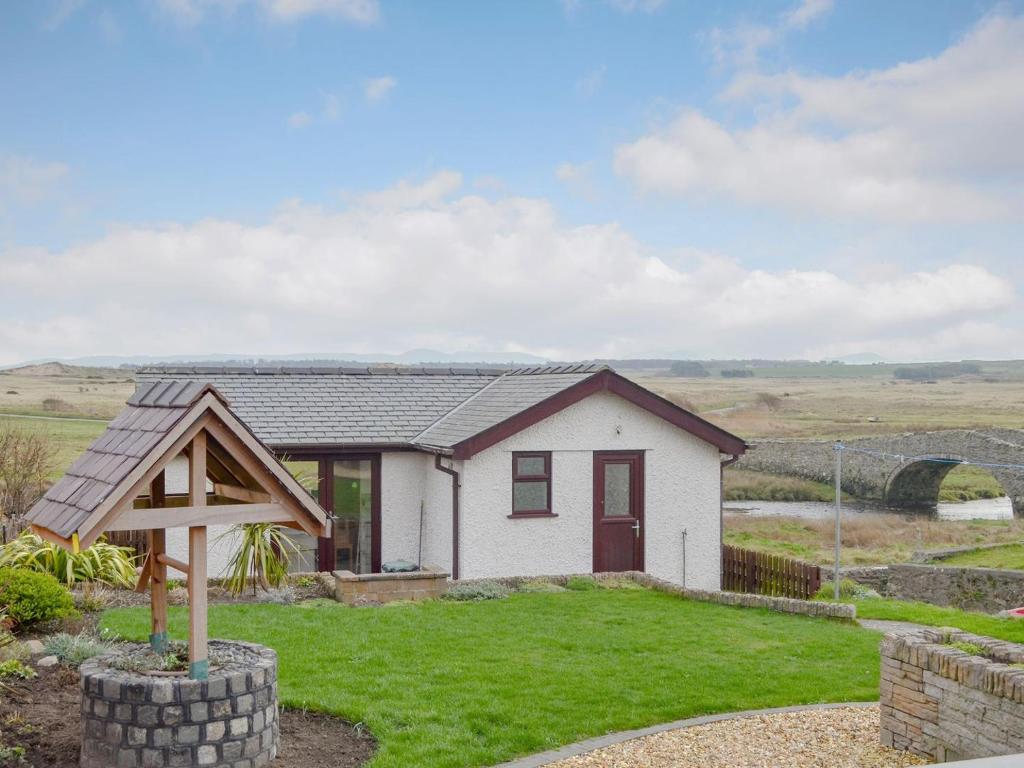 a small white house in the middle of a field at Hafan in Aberffraw