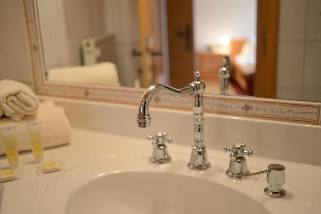 a bathroom sink with a faucet and a mirror at Alpengasthof zur Post in Schattwald