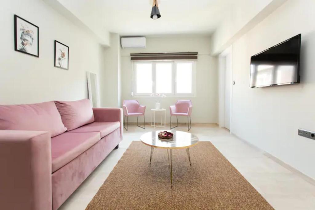 a living room with a pink couch and a table at Tsimiski #apartment (one bedroom) in Thessaloniki