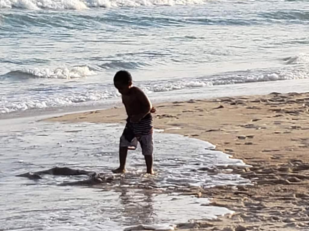 Un ragazzo in piedi sull'acqua sulla spiaggia di 4 Sea Monkeys Apt. #3 a Surf City