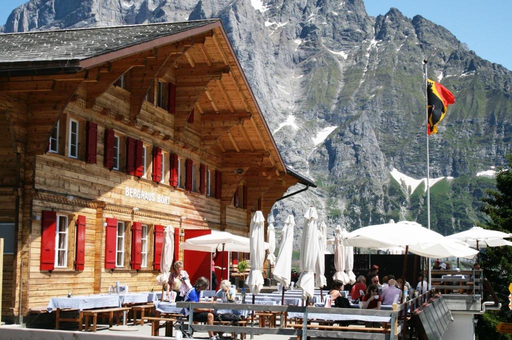 a restaurant with tables and umbrellas in front of a mountain at Alpinhotel Bort in Grindelwald