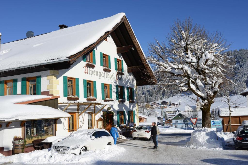 a man standing in front of a building in the snow at Alpengasthof zur Post in Schattwald