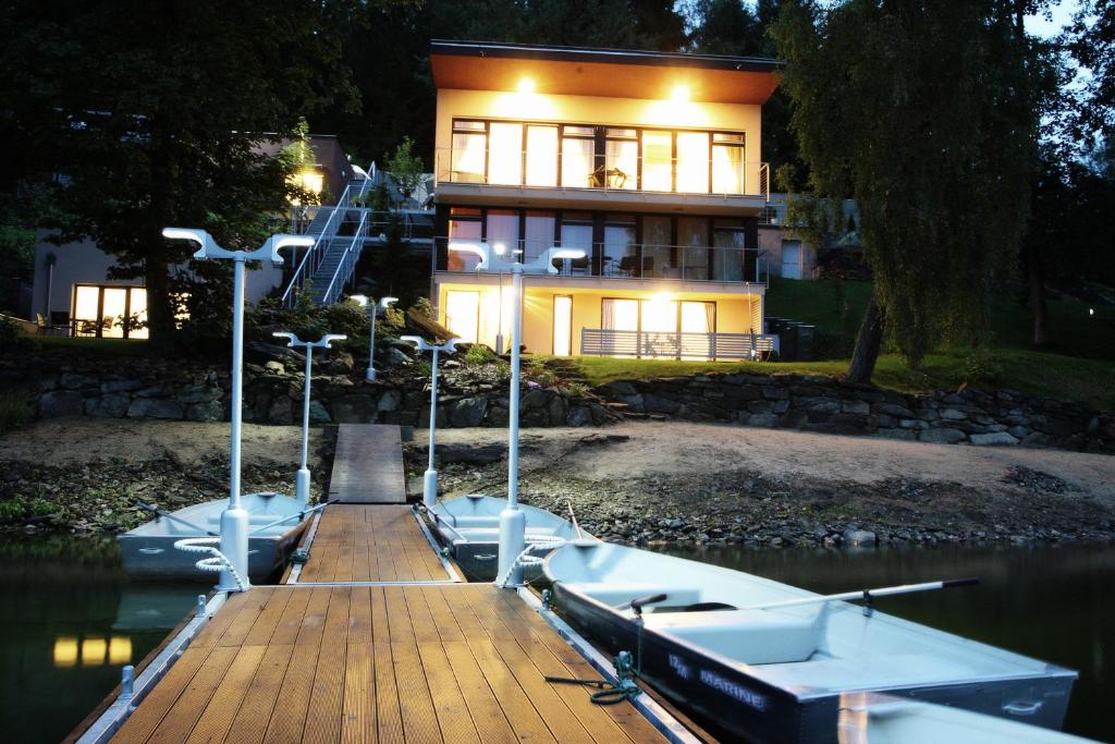 a house on the water with a boat on a dock at Apartmány Bella Vista Lipno in Frydava