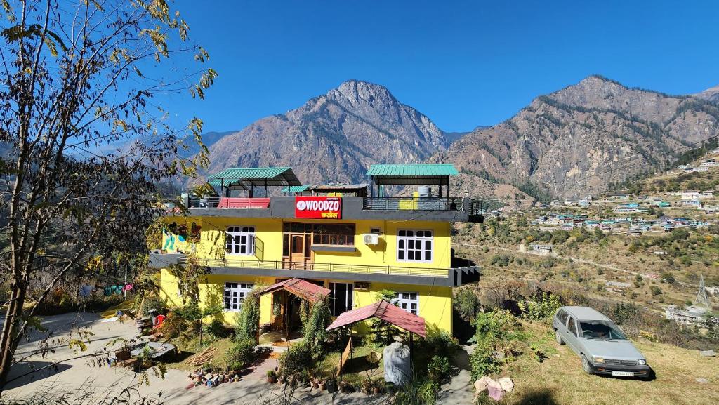 a yellow building with a car parked in front of it at Woodzo Kasol in Jari