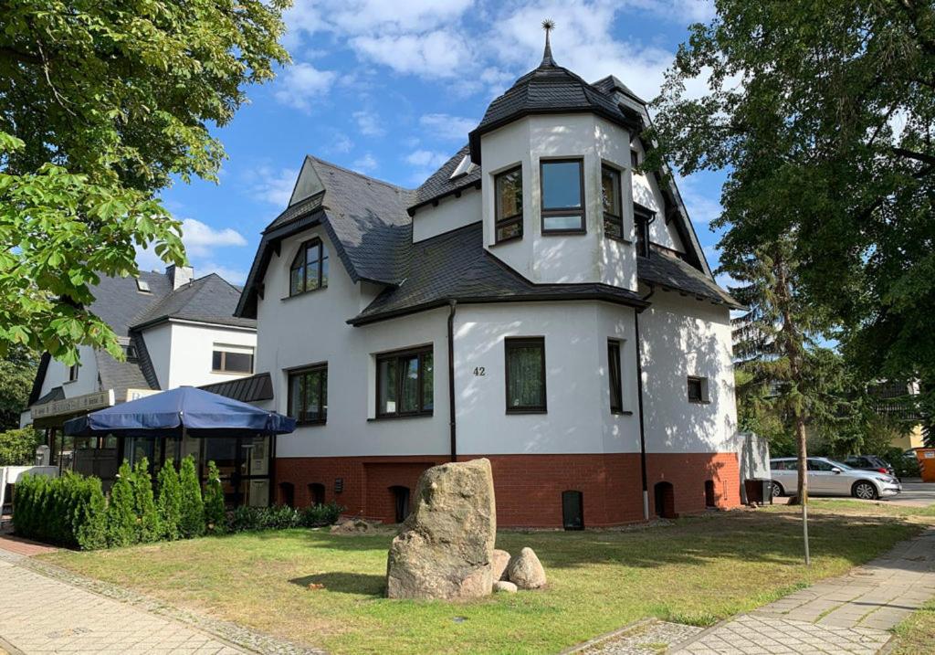 une grande maison blanche avec un toit noir dans l'établissement Hotel Blaufuchs, à Petershagen